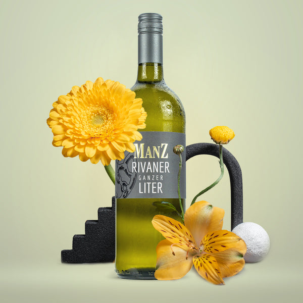 Eine Weinflasche Manz, Rivaner, Trocken, 1 Liter-Flasche, um der Flasche herum sind diverse gelbe Blumen.
